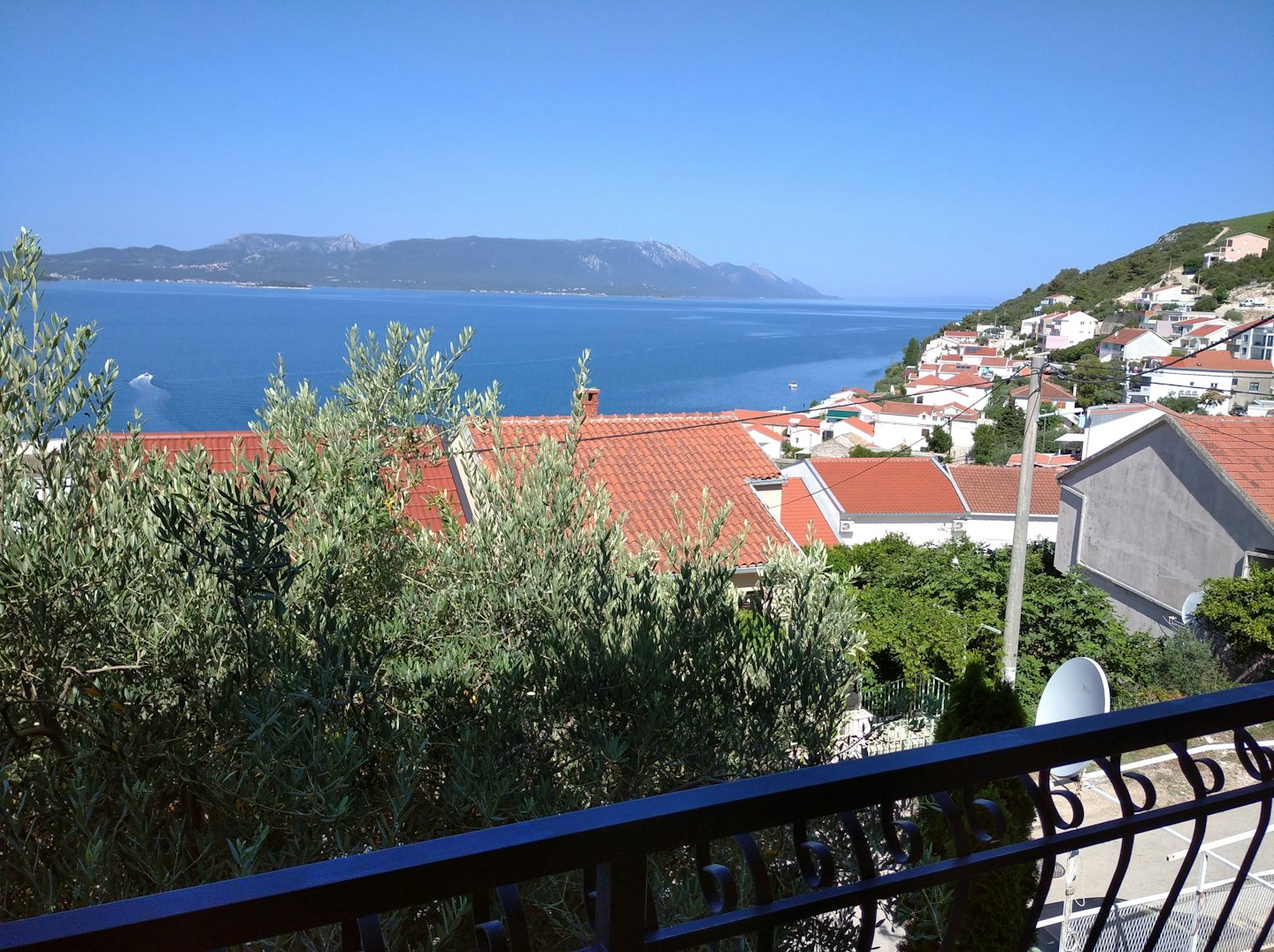 Mediterrane Dorfhäuser mit Blick auf eine Küstenbucht mit einem Boot.