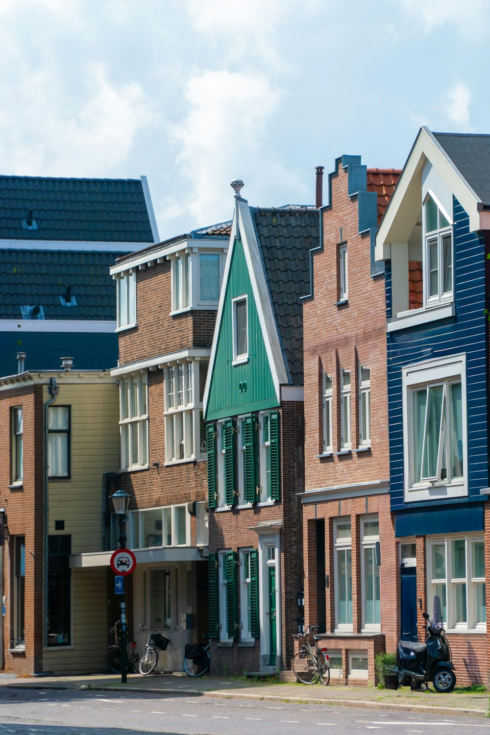 Bunte traditionelle Häuser säumen eine ruhige Stadtstraße mit geparkten Fahrrädern.