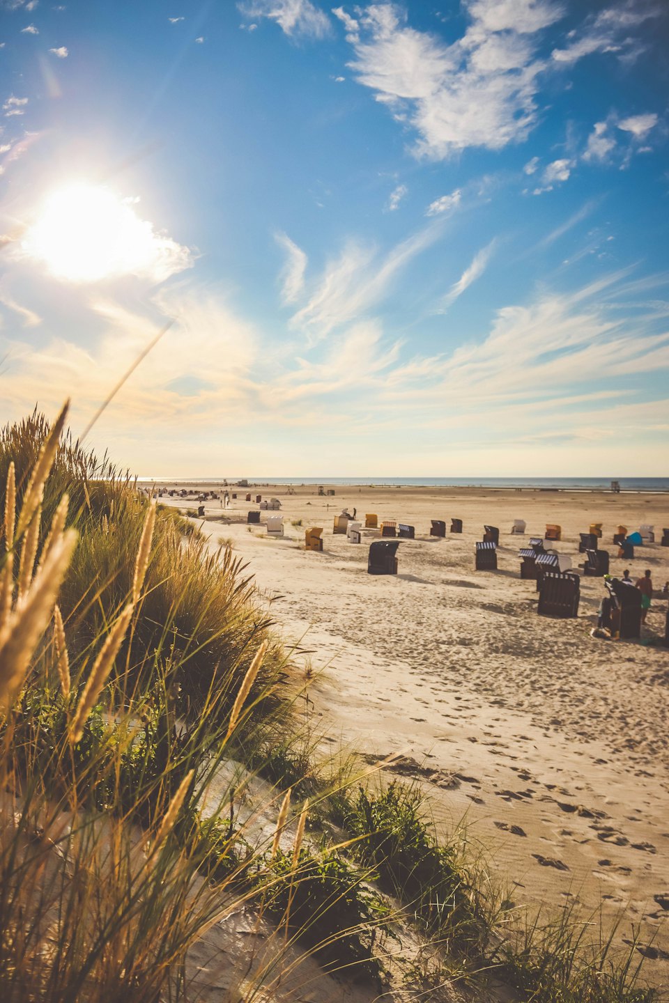 Sonnenliegen stehen am sonnigen Strand mit dem Meer im Hintergrund.